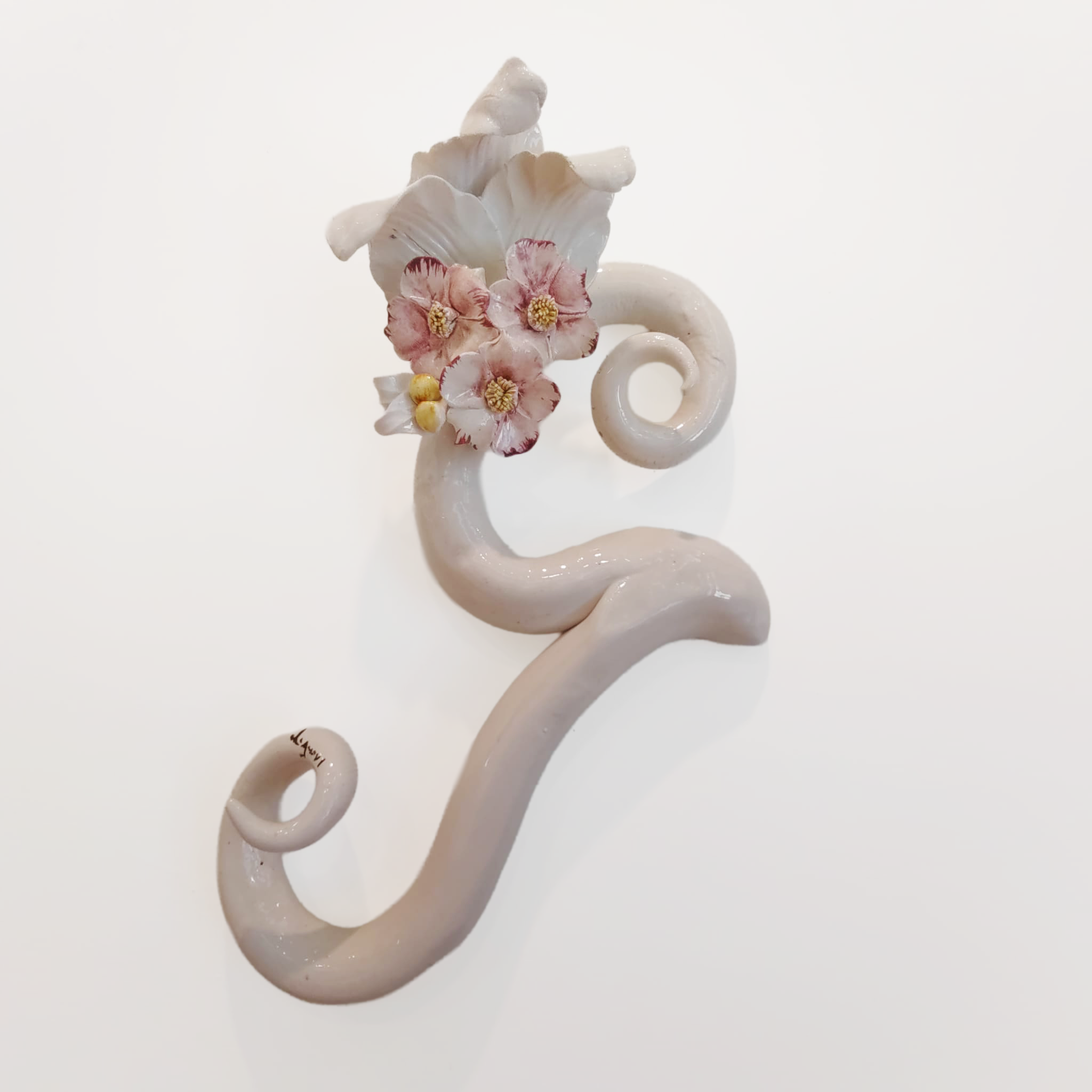 Iniziale decorativa in ceramica bianca con fiori