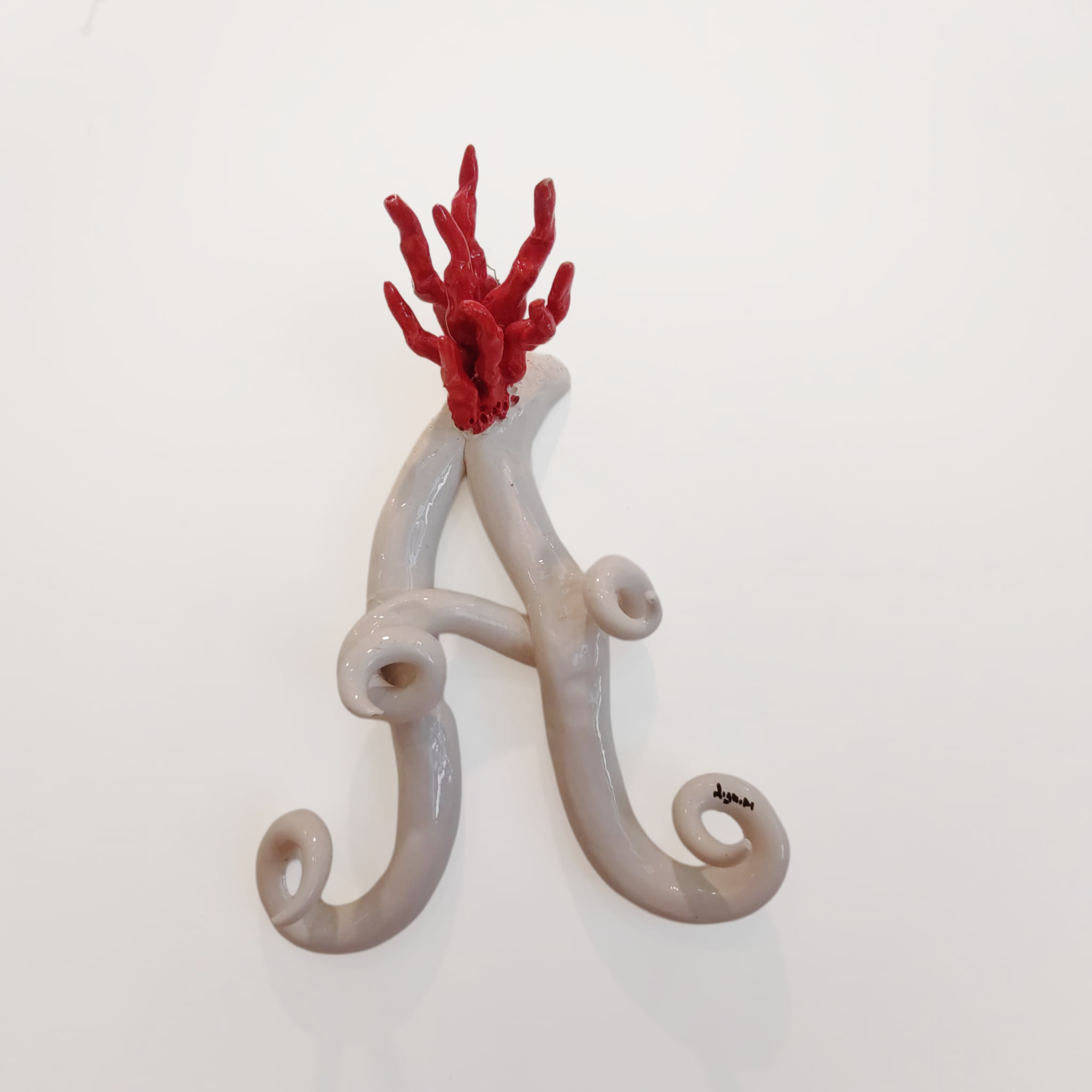 Iniziale decorativa in ceramica con corallo