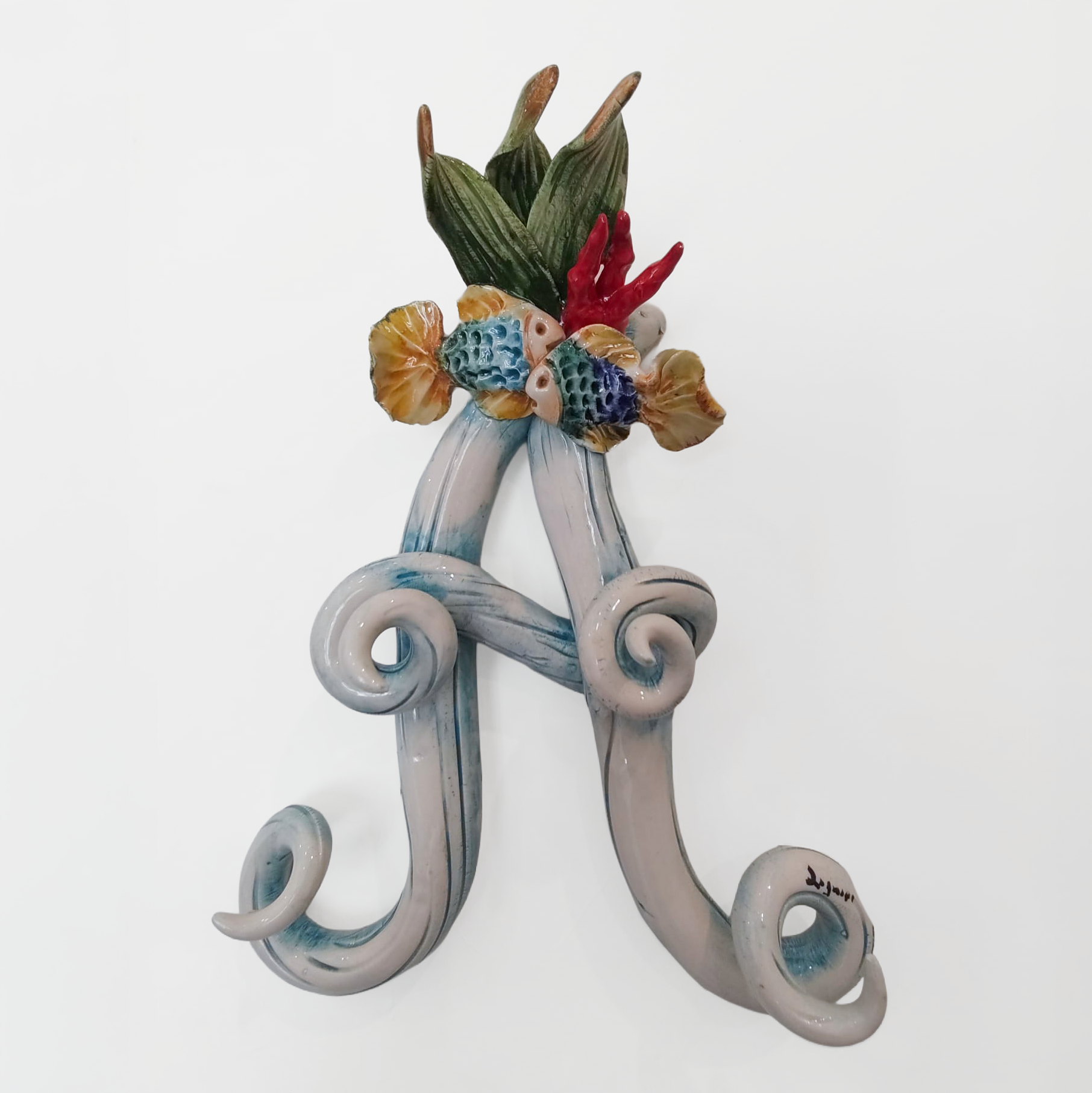 Iniziale decorativa in ceramica con elementi marini